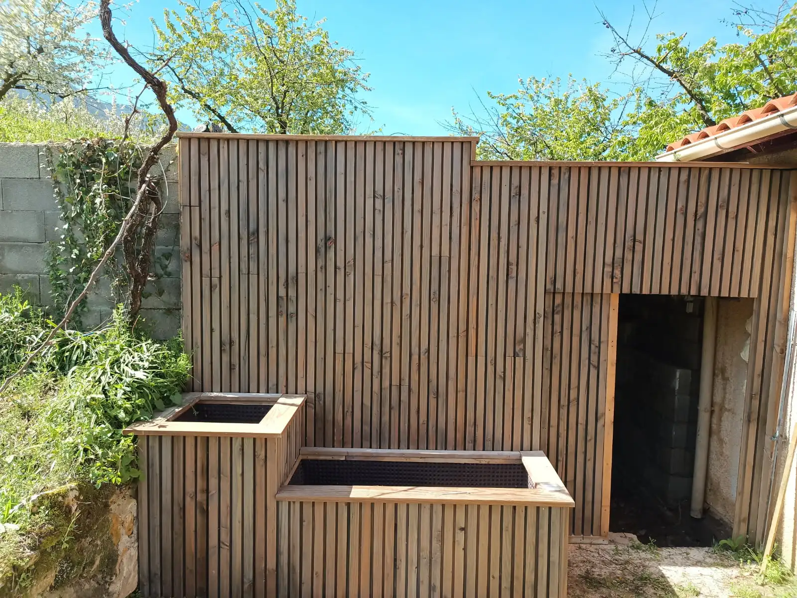 Après : mur rénové avec bardage bois et bacs habillés en bois